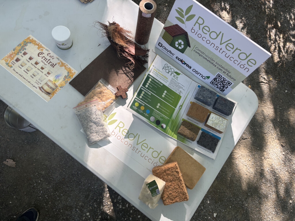 Mesa expositiva de RedVerde con muestras de materiales naturales y reciclados utilizados en bioconstrucción y economía circular durante una jornada educativa en Málaga.
